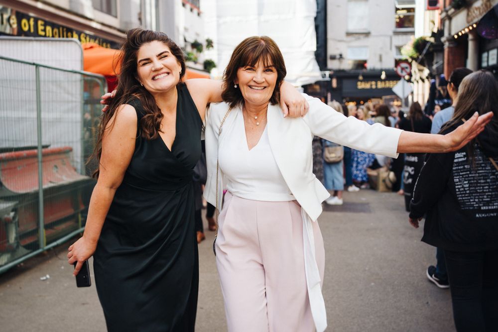 Two friends in contrasting black and white outfits walk together smiling on a city street.