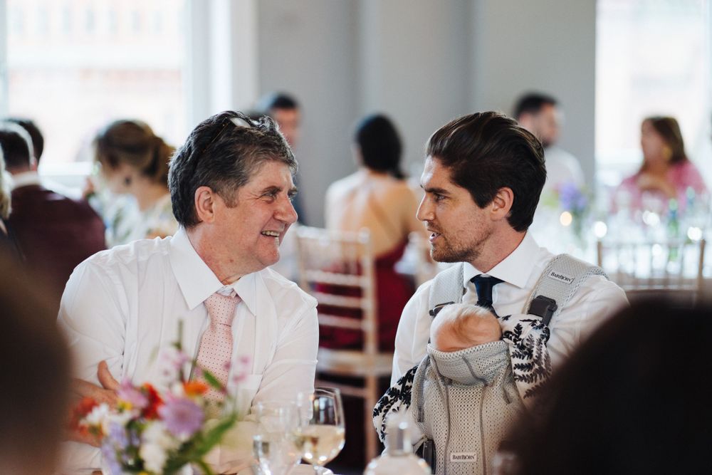 Two guests in formal attire having animated conversation at wedding reception.