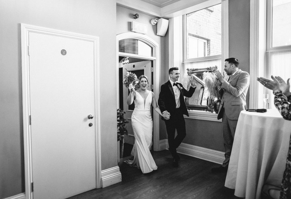 Wedding celebration entrance in black and white with guests applauding.