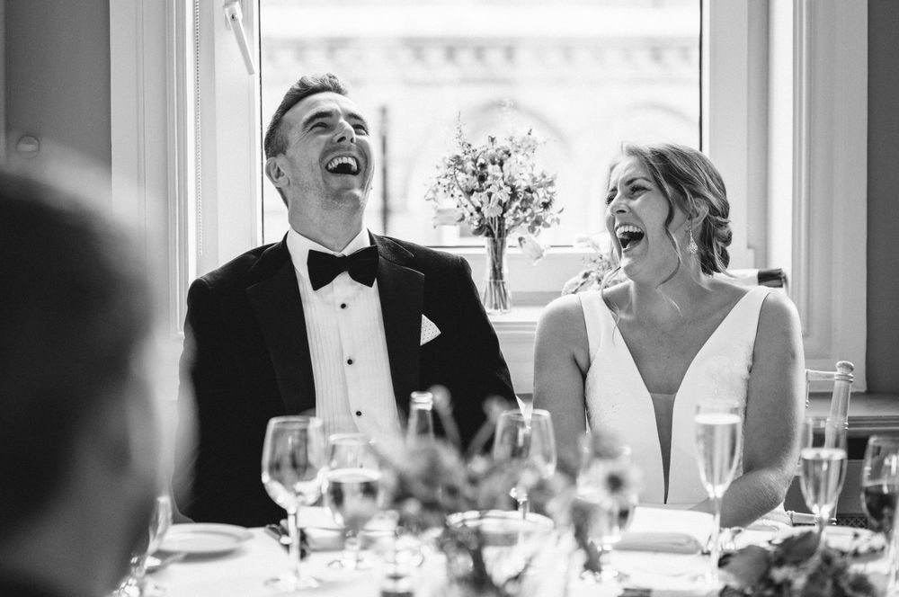 Wedding couple sharing a laugh during reception dinner with elegant table settings.