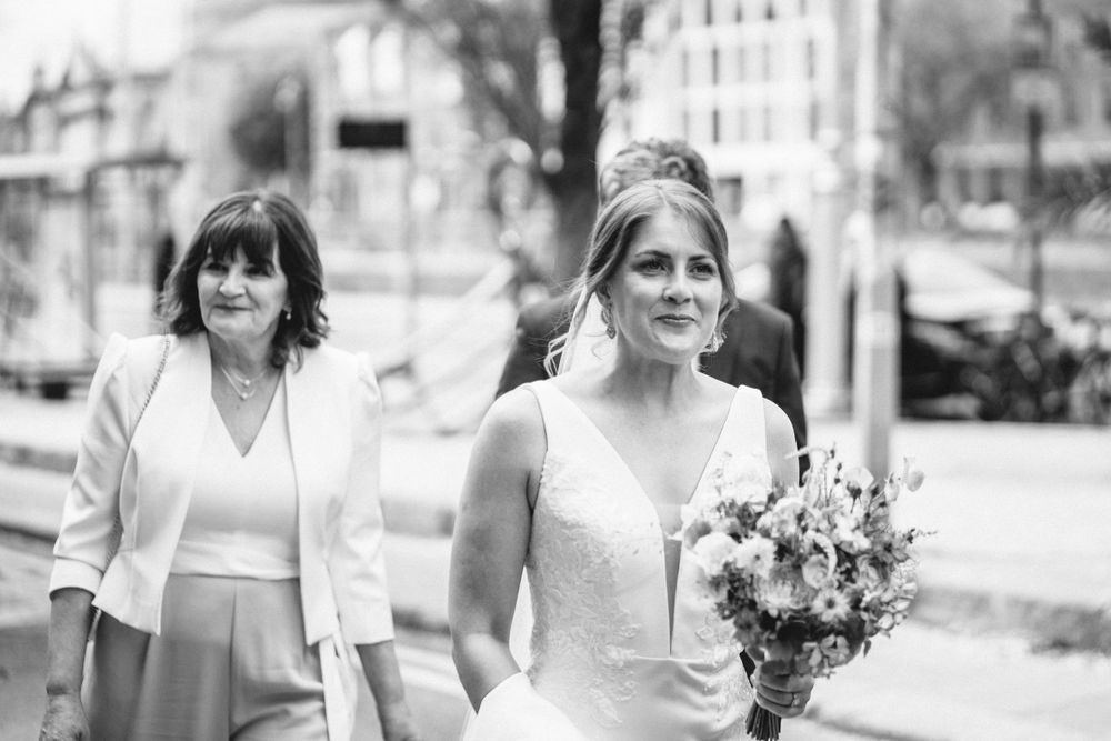 Black and white wedding photo showing two people walking together on a city street.