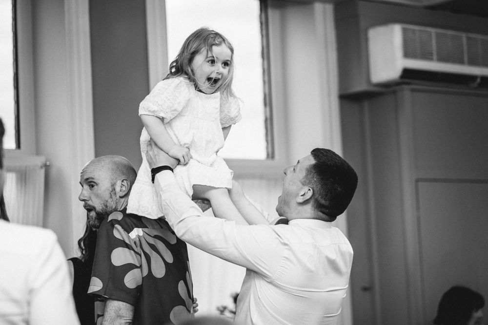 Sweet celebration moment with child being lifted during wedding reception.