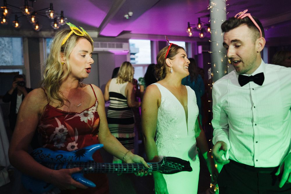 DJ entertaining guests at nighttime wedding reception with colorful lighting.