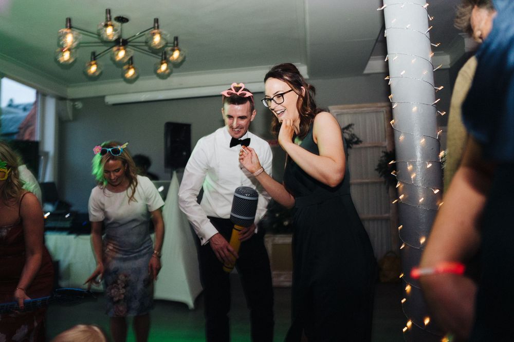 Partygoers dancing and having fun in a decorated indoor space with string lights.