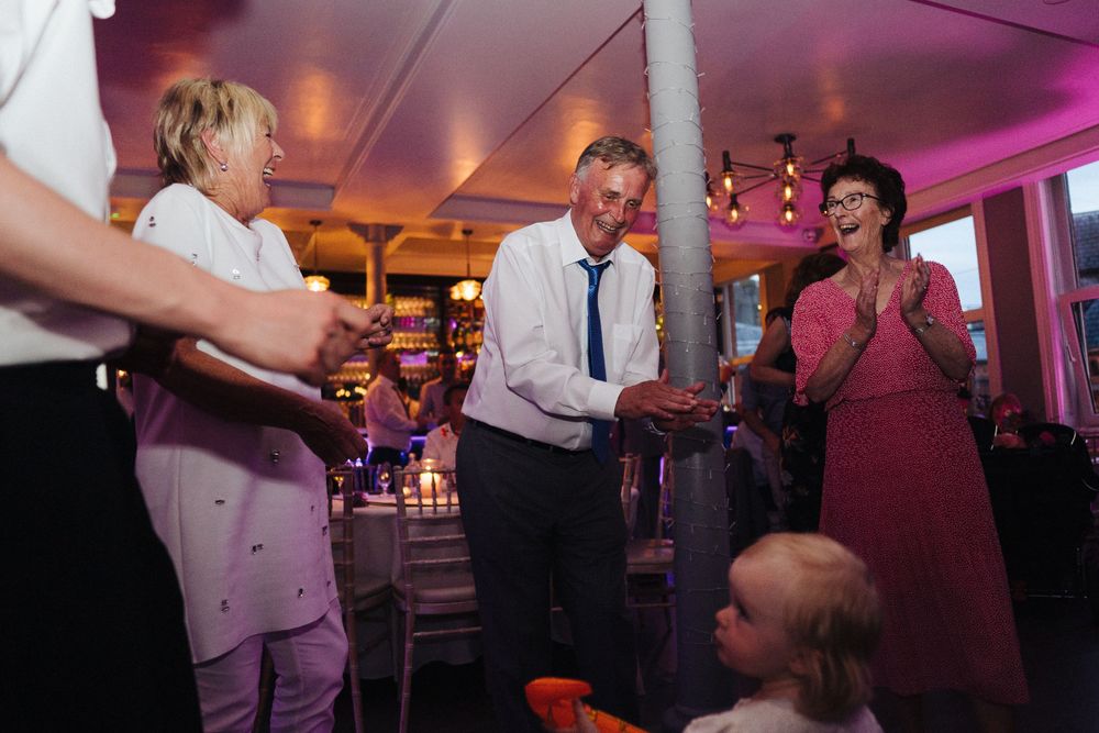 Evening celebration with guests mingling under ambient purple lighting and decorative fixtures.