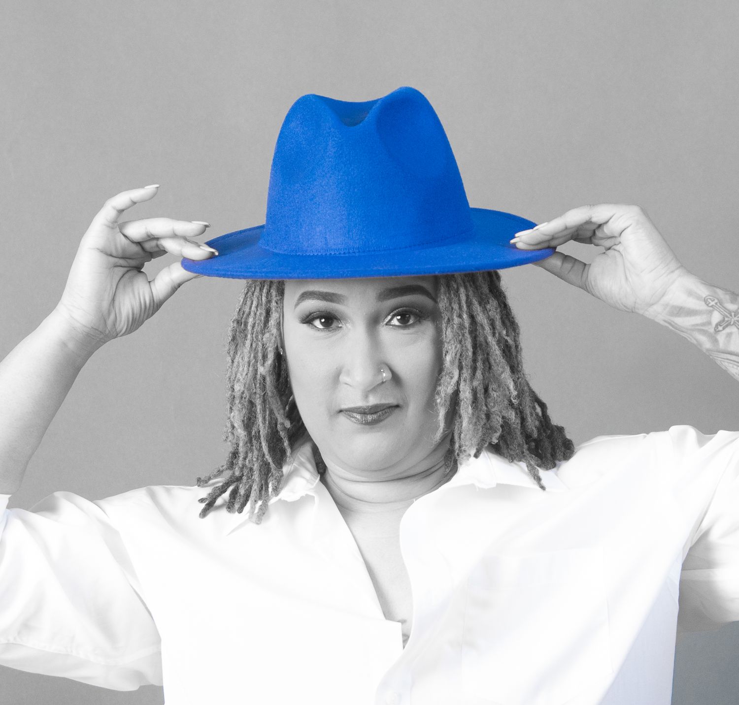 Artistic black and white portrait with vibrant blue fedora hat.