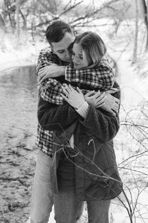 A black and white portrait of a couple embracing outdoors in winter.