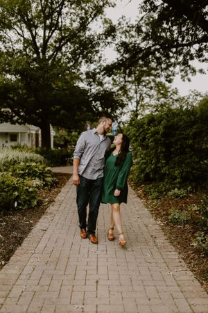 Couple walking together on brick path surrounded by lush greenery.