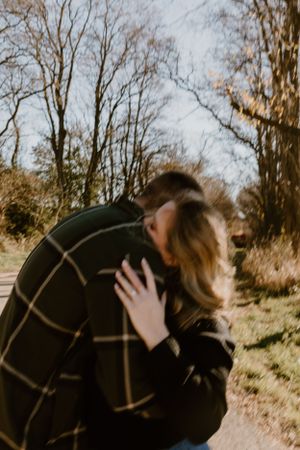 A couple sharing an intimate moment on a wooded path during autumn.
