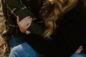 Close-up view of hands holding with bare trees in the background.