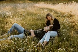 A couple relaxing together in a sun-drenched field of wildflowers.