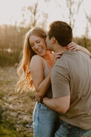 Joyful couple sharing intimate moment while embracing in natural outdoor setting.