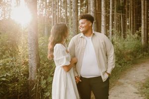 Couple shares a romantic moment on a sunlit forest path during golden hour.