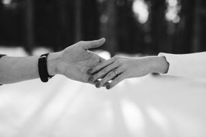 Black and white close-up of two hands reaching out to hold each other.