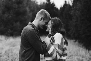 Intimate black and white portrait of couple sharing a tender forehead touch outdoors.