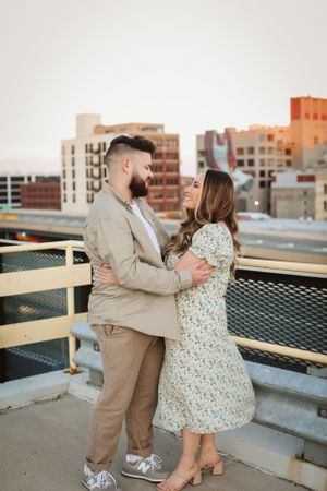 A couple embraces on a city rooftop during a warm sunset.
