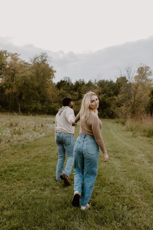 Two people walking through a grassy field on an autumn afternoon.