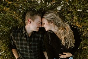 An intimate moment shared between a couple lying in a field of flowers.
