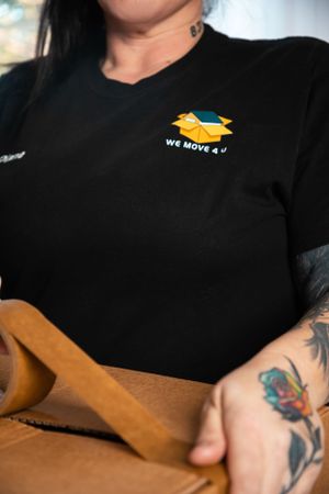 Close-up of moving company uniform showing logo and tattoo on worker's arm.
