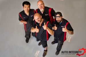 Group of auto service professionals posing together in repair shop.