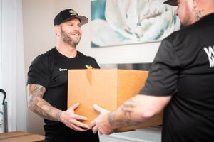 Moving professionals collaborate while handling packages in bright indoor setting.