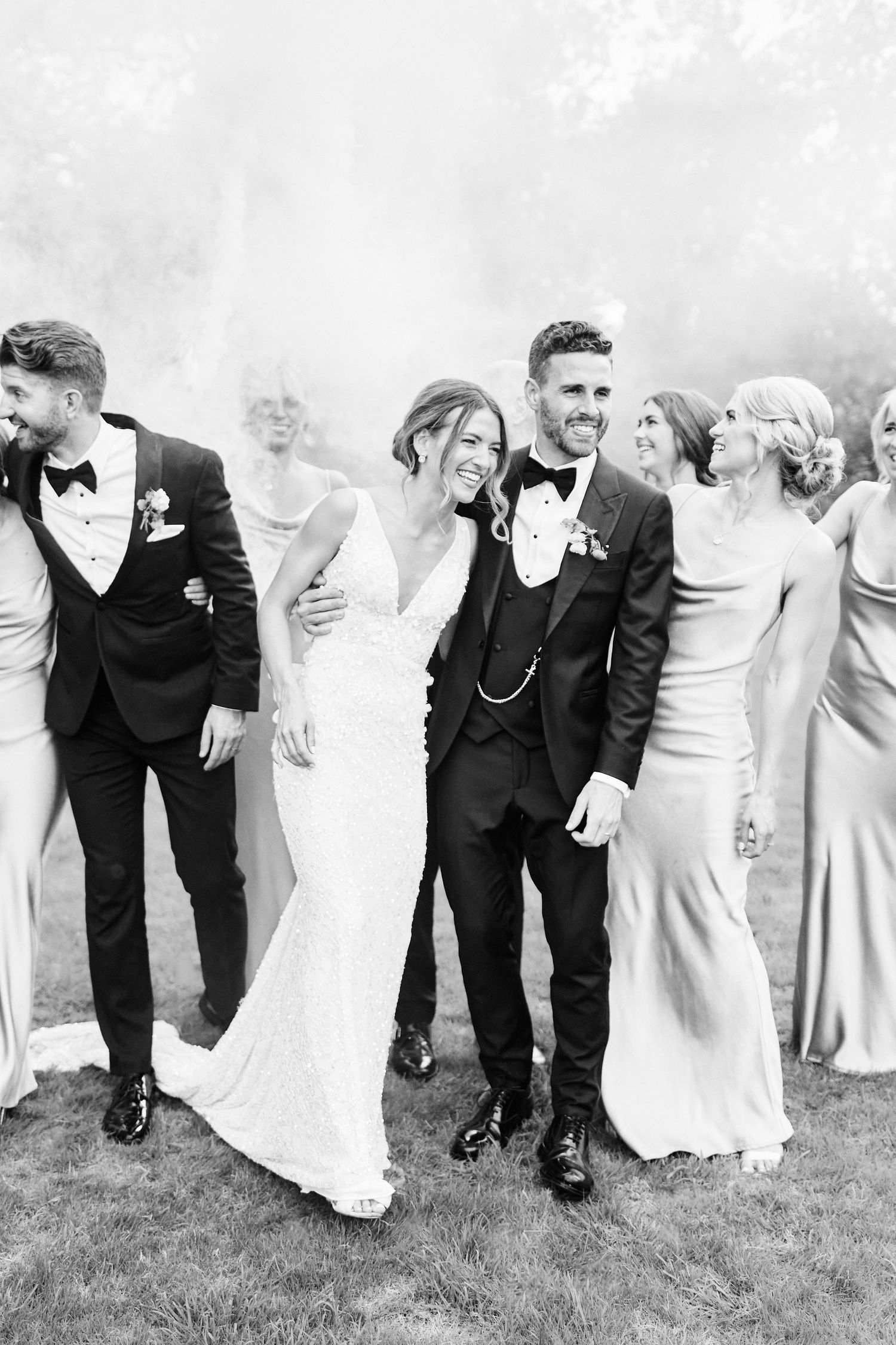 bride and groom walk through smoke with wedding party at luxury essex wedding. by an award winning Norfolk photographer