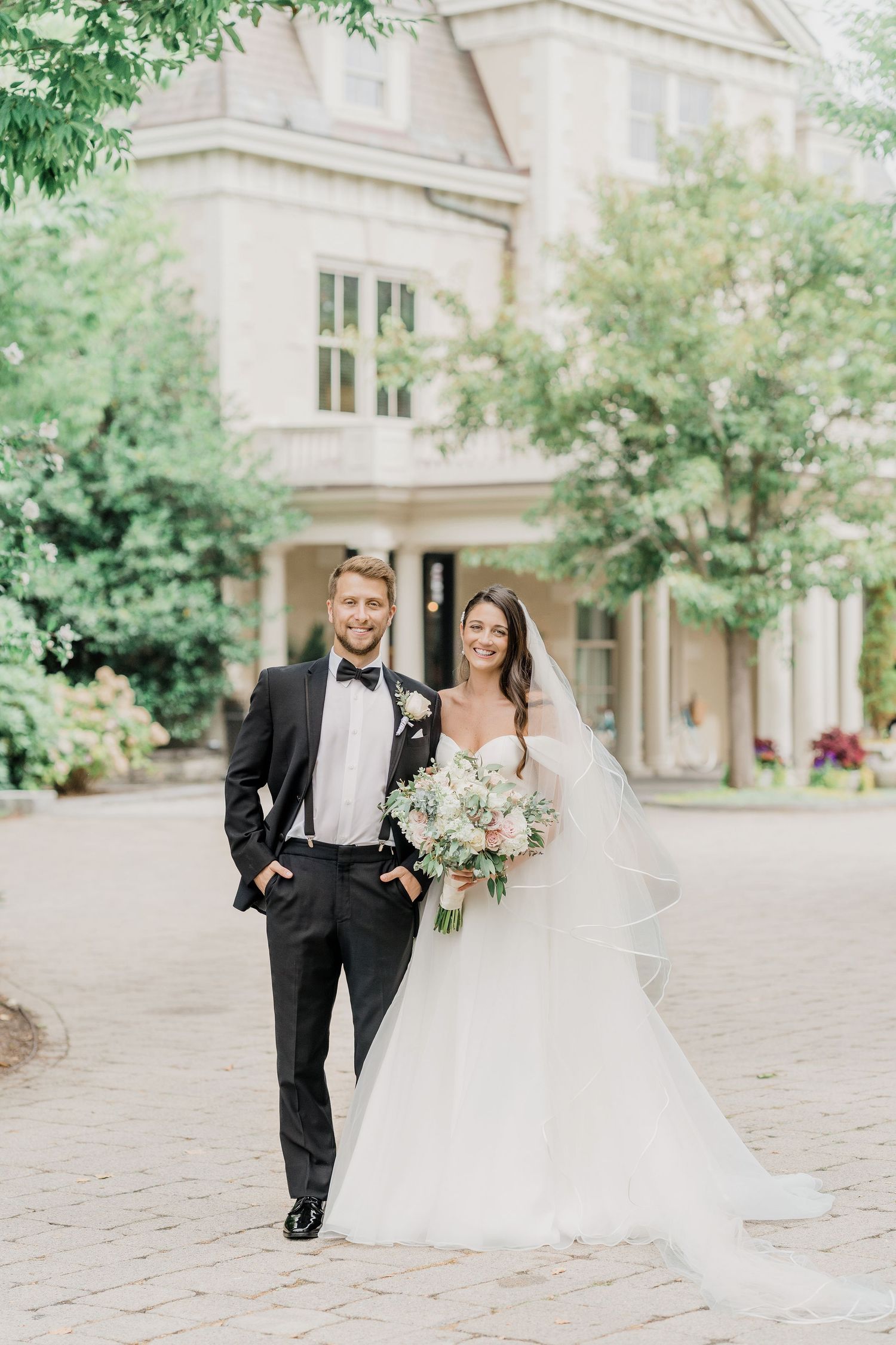 Bride and groom smiling in wedding portrait in front of historic Chanler Inn near Cliff Walk in Newport RI