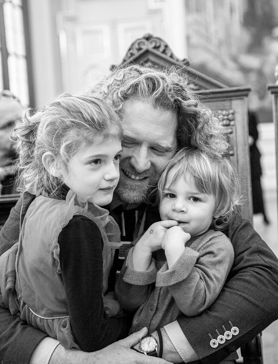 Black and white portrait capturing a tender moment between parent and children.
