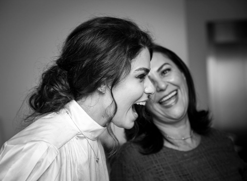 Black and white candid photo capturing two people sharing a joyful laughing moment together.