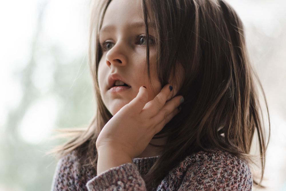 candid portrait of young child with a serious gaze off to her right.