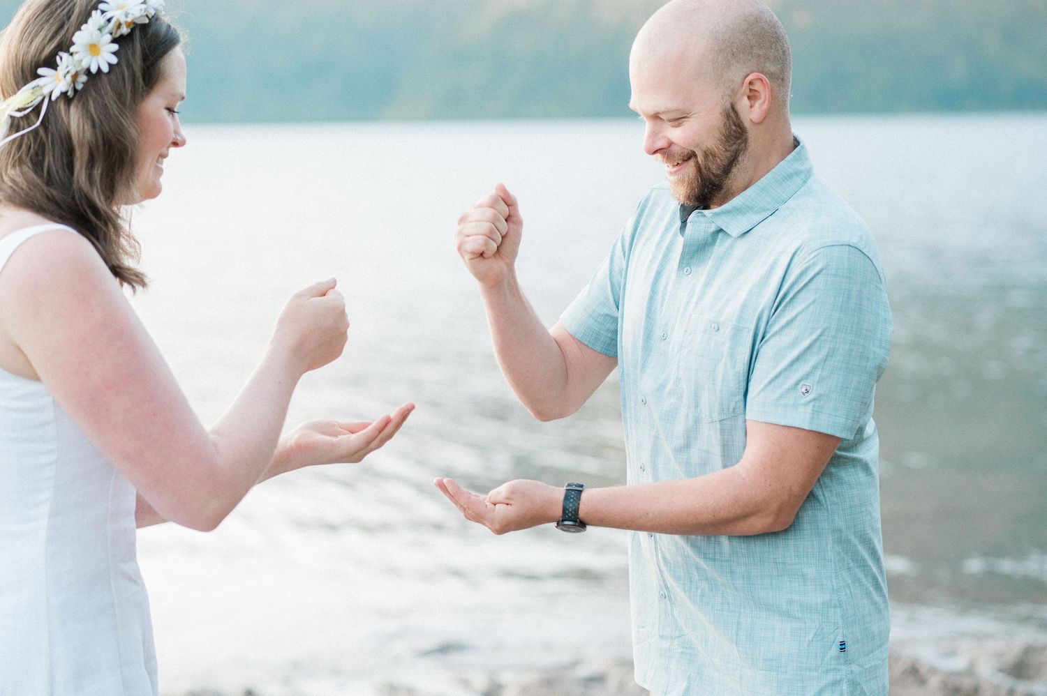 Couple plays rock, paper, scissors in front of Lake Crescent