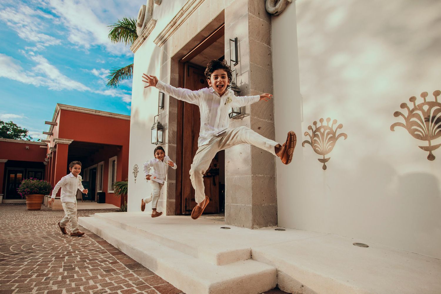 Joyful jumping celebration shot outside a white Spanish-style building.