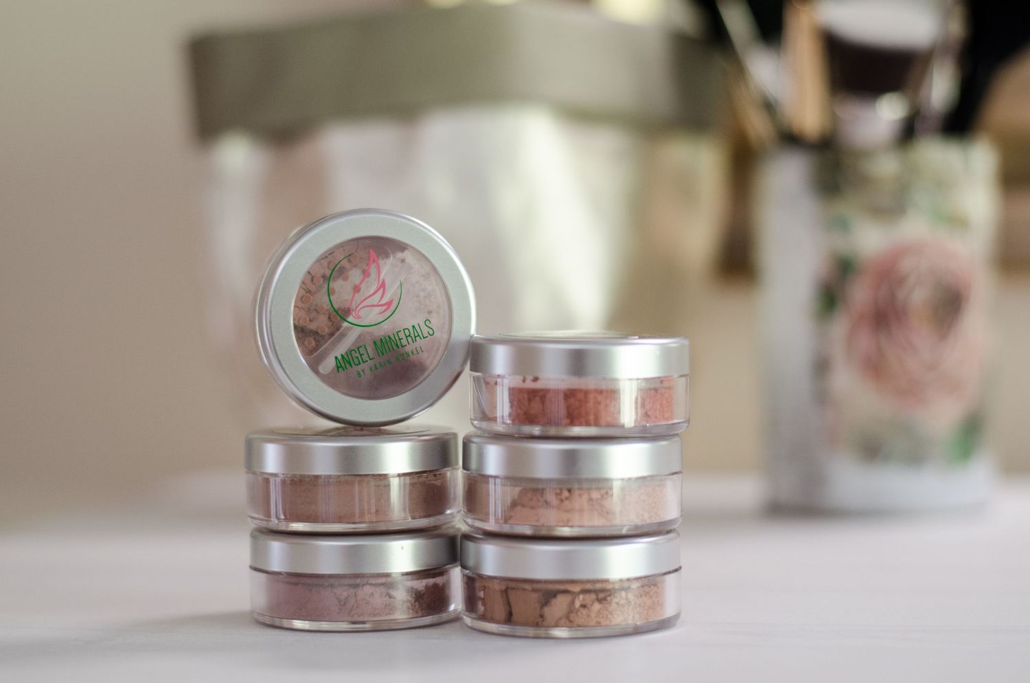 Vintage-style cosmetic jars with rose patterns lined up on white surface.