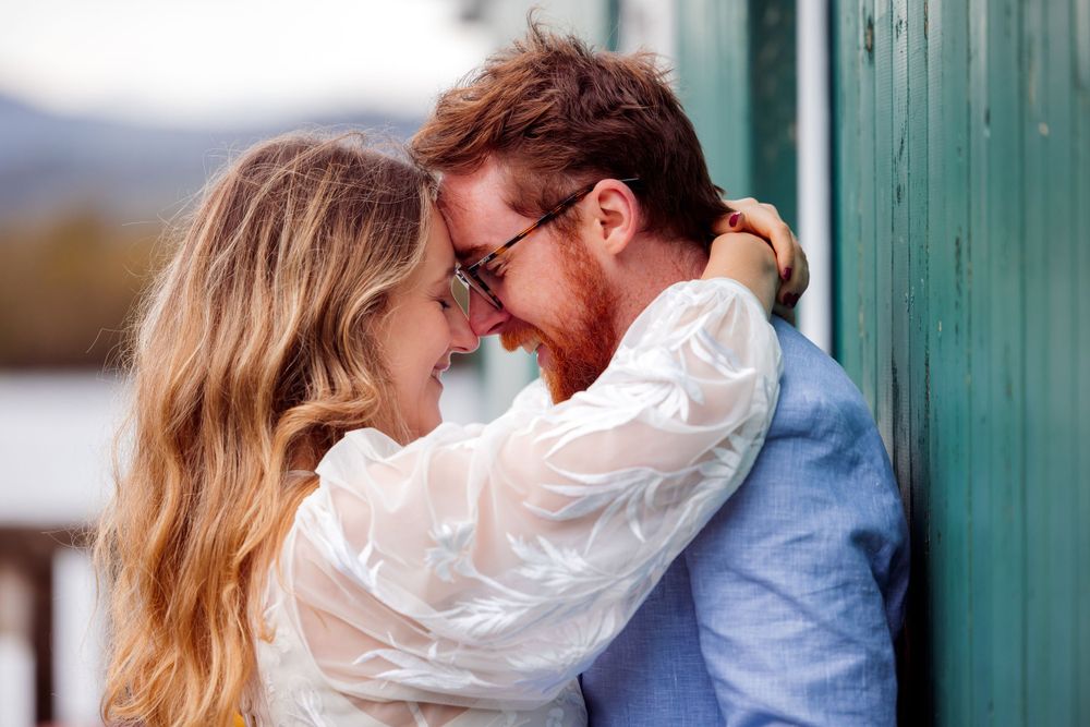 A romantic moment between a couple against a green wall with mountains in the background.