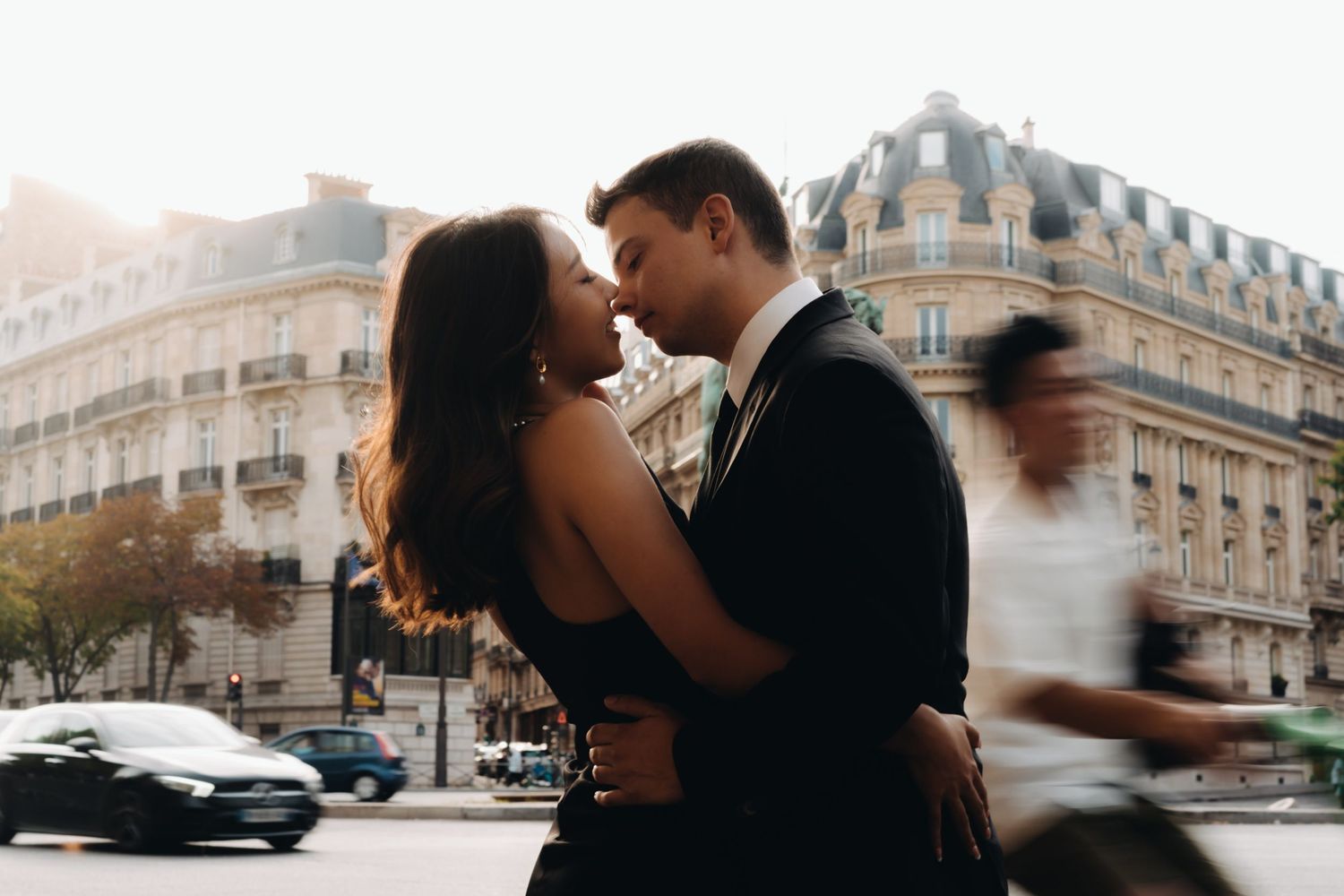 Romantic couple embracing on a Parisian street with classic architecture in the background.