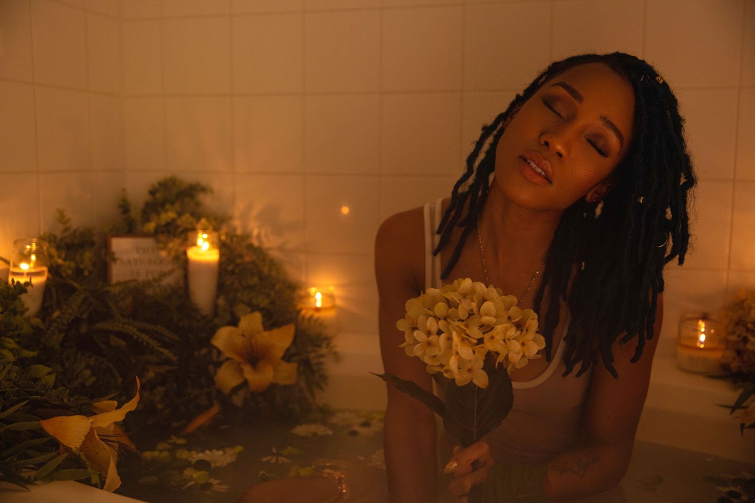 Dondria Nicole sitting in a bath decorated with flowers and candles.