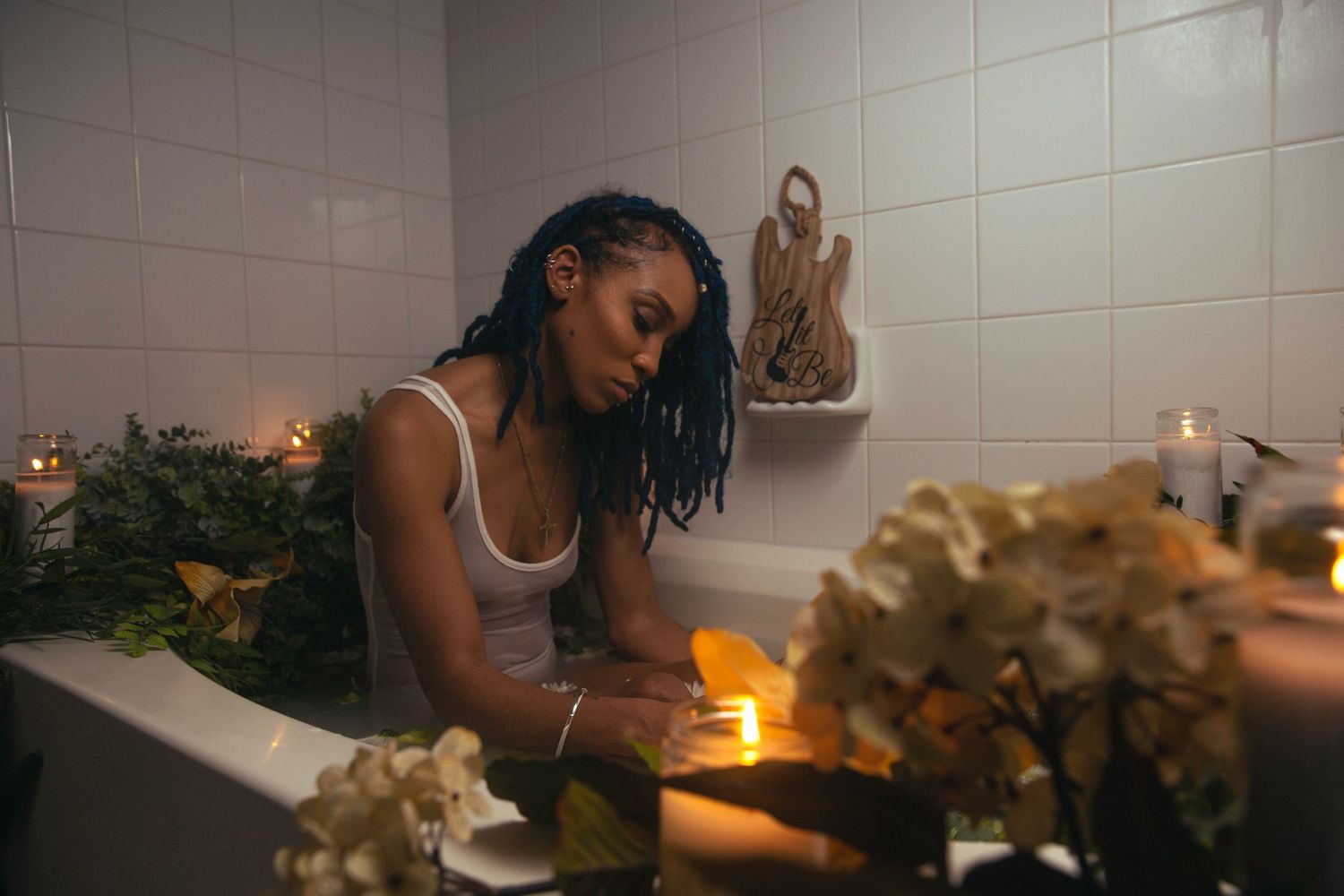 Dondria Nicole sitting in a bath decorated with flowers and candles.