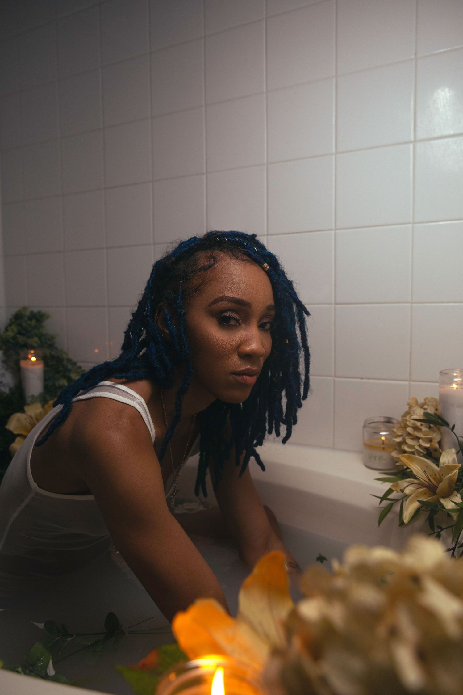 Dondria Nicole sitting in a bath decorated with flowers and candles.