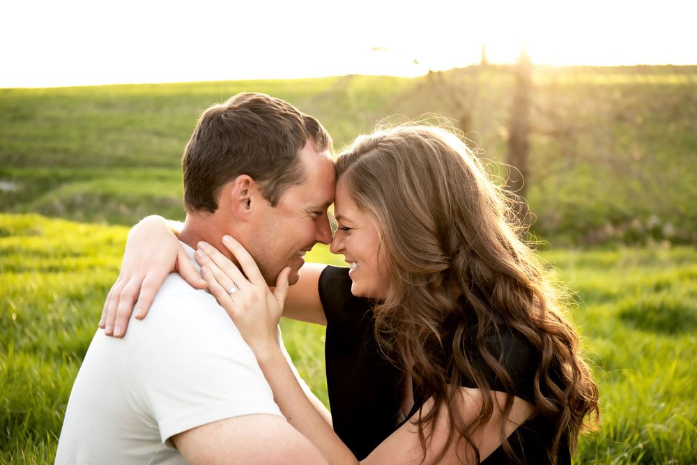 An intimate moment captured between a couple in a sunlit meadow during golden hour.