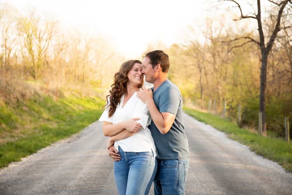 A romantic moment shared between a couple on a country road surrounded by spring foliage.