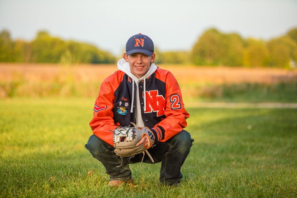 Person wearing a baseball cap sitting in green grass during sunset.