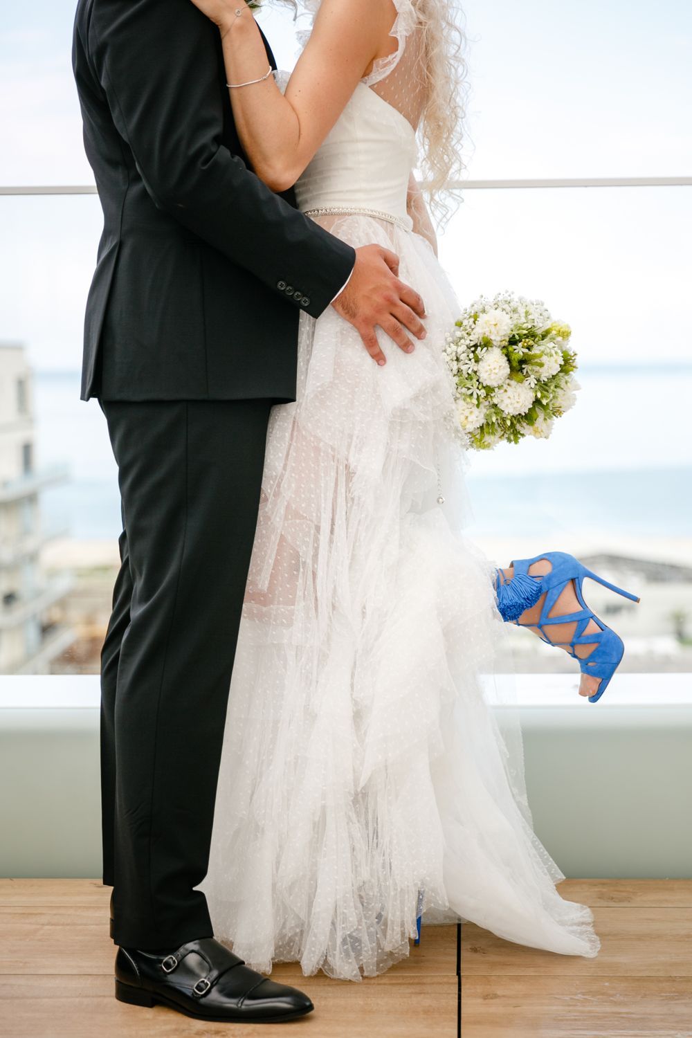 Close up of bride and groom hugging after the civil ceremony at Nyota Hotel Mamaia. She hase stunning wedding blue shoes