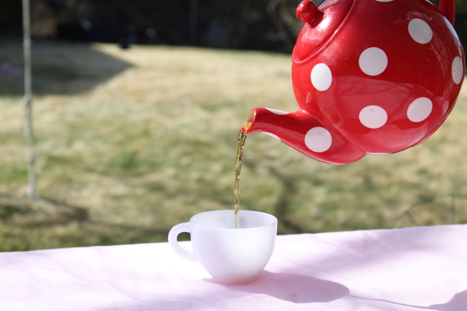 Polka dot tea pot pouring tea into a cup