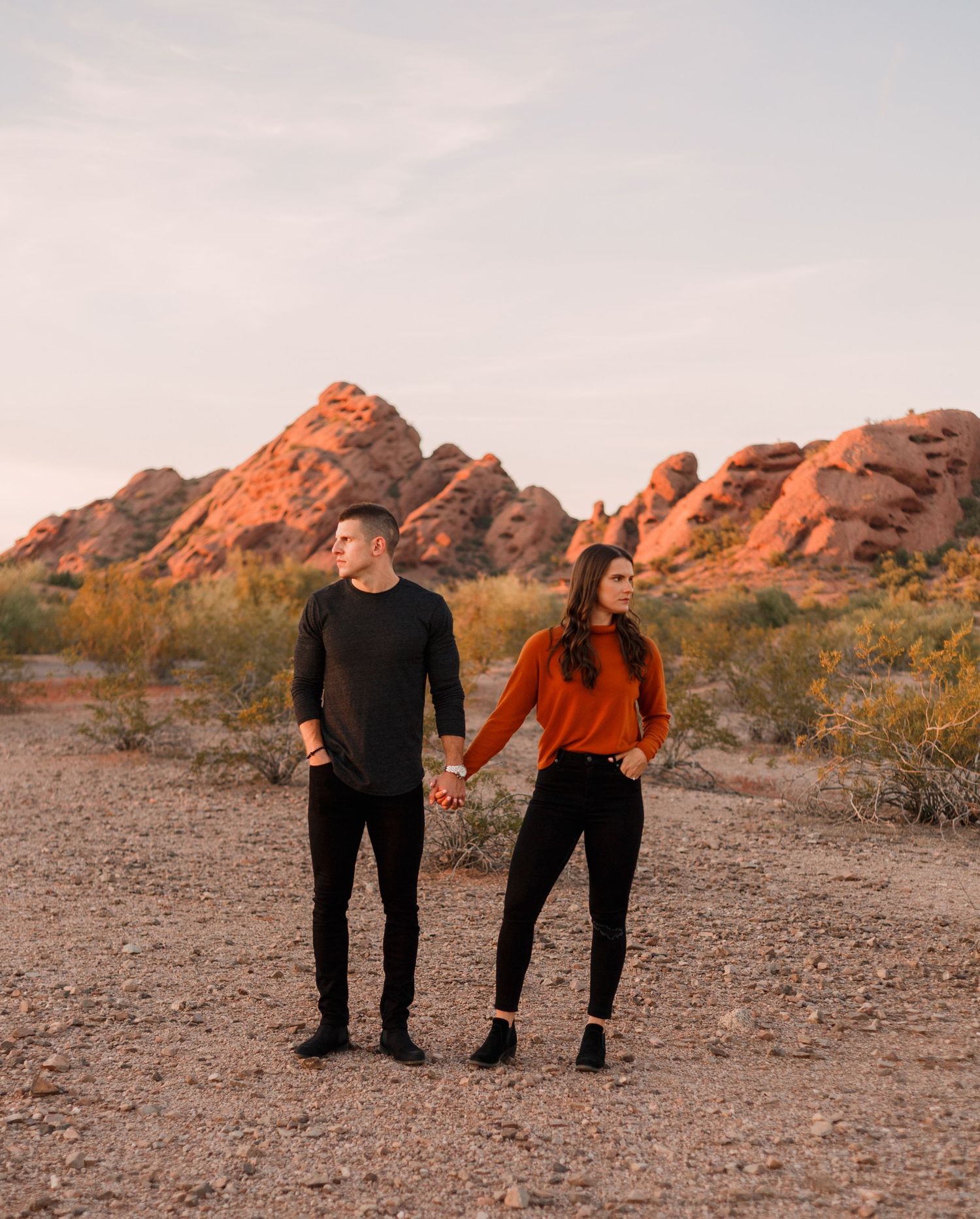 engaged couple holds hands in a desert landscape
