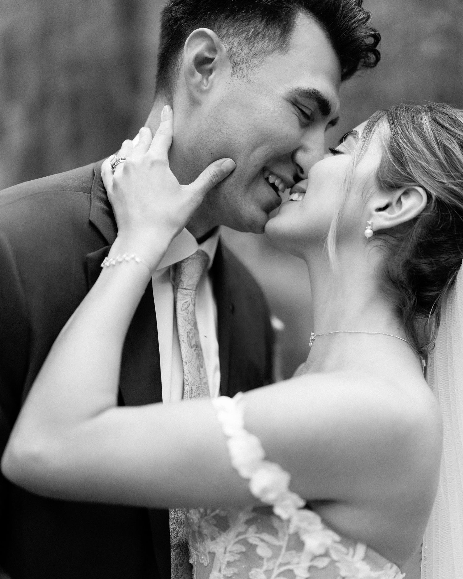Black and white photo of smiling bride and groom sharing an intimate moment on their wedding day.
