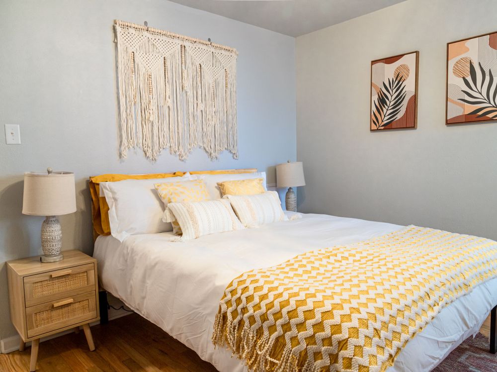 Modern boho bedroom with macrame wall hanging, geometric throw and wooden nightstand.