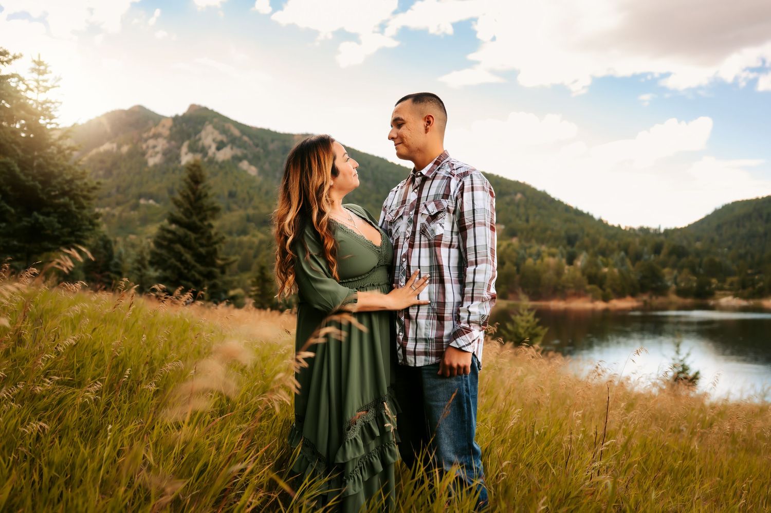 Couple sharing romantic moment in mountain meadow by lake.
