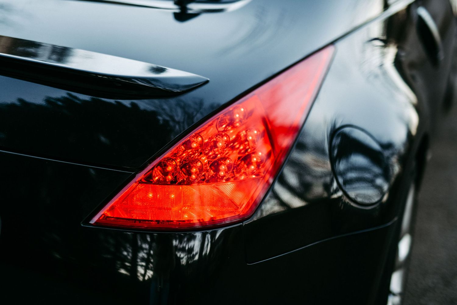Close-up of red LED tail light on a black sports car.