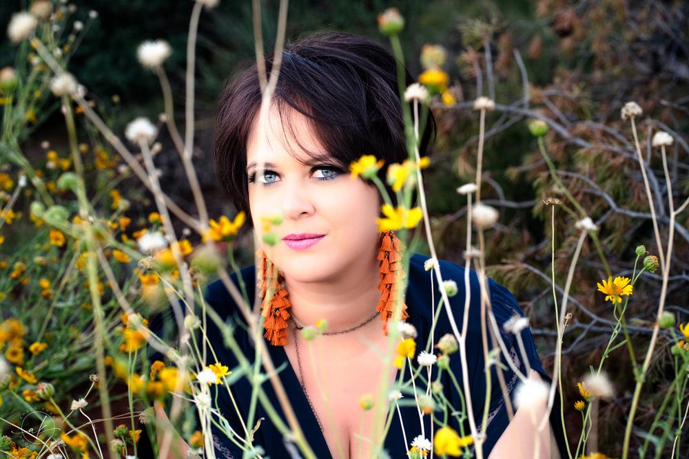 Portrait in a wildflower field with yellow blooms and natural sunlight creating a dreamy outdoor scene.