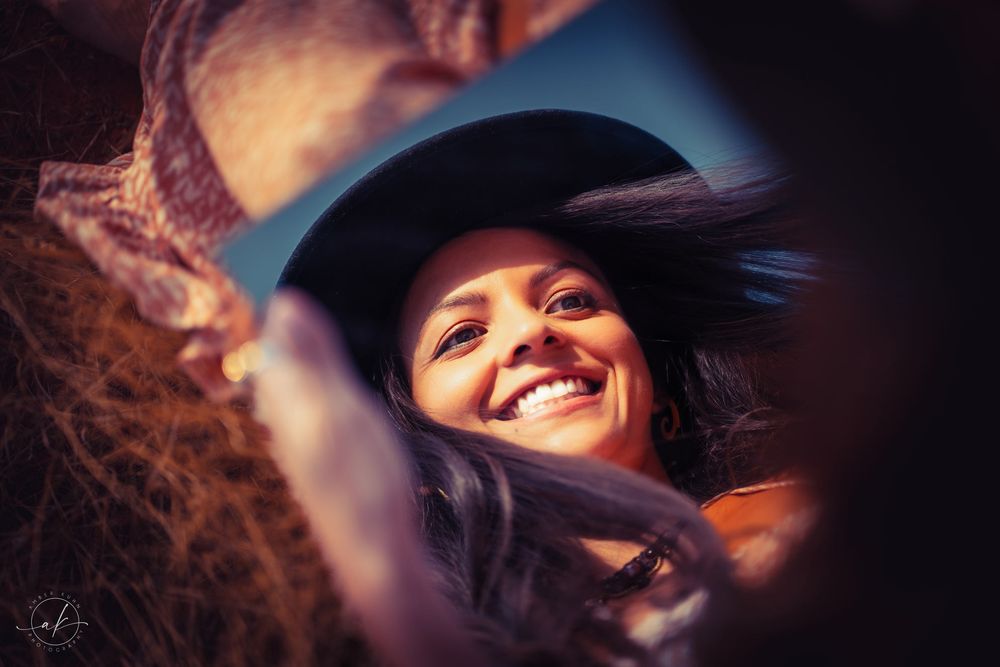 Creative mirror reflection portrait with black hat capturing joyful expression.